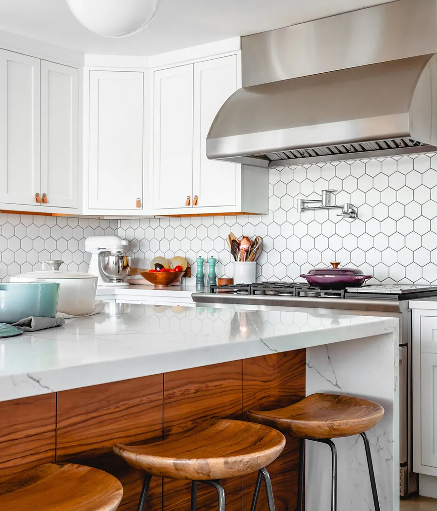 White kitchen with hexagon tile backsplash, wood bar stools, and pendant lighting