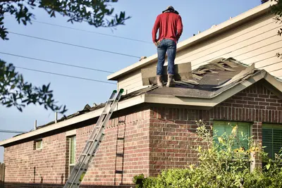 Roofer repairing asphalt shingles on a residential roof